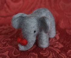 a small gray elephant with a red heart in its trunk on a red background,