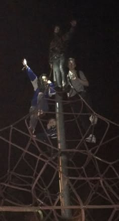 people standing on top of a metal structure at night