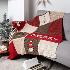 a couch with a knitted christmas blanket on it and a book next to it