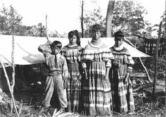 an old black and white photo of three women standing in front of a tent