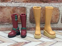 three pairs of boots are lined up against a brick wall