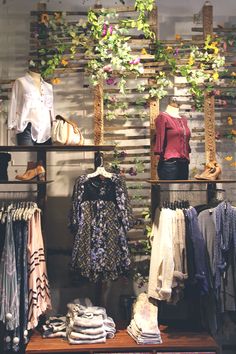 a clothing store display with clothes and flowers