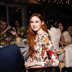 a woman sitting at a table in front of a man who is talking to her