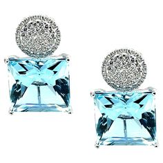 These bold earrings feature two spectacular square-cut aquamarines that weigh a total of 26 carats. The aquamarines have a deep blue color and are very large, measuring 15mm across. It is highly unusual to find a beautifully matched pair of aquamarines of this large size. They are brilliant-cut, similar to princess-cut diamonds, which gives them additional brilliance and life! Over a hundred white diamonds are pave-set in 18k white gold solid circles with outer frames that sit above the aquamari Luxury Blue Diamond Earrings With Accents, Luxury Blue Diamond Earrings For Formal Events, Luxury Blue Diamond Earrings For Formal Occasions, Luxury Blue Topaz Earrings, Blue Brilliant Cut Earrings For Evening, Brilliant Cut Blue Earrings For Evening, Luxury Aquamarine Blue Earrings, Luxury Blue Aquamarine Earrings, Luxury Blue Topaz Blue Earrings