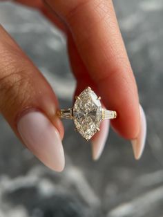 a woman's hand holding an engagement ring with a diamond on the middle finger