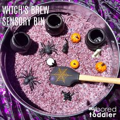 a bowl filled with halloween decorations on top of a purple cloth covered table next to two black jars