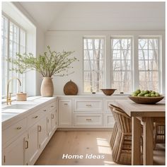 a kitchen filled with lots of white cabinets and counter top next to a wooden table