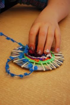 a child's hand on a string attached to a paper plate that is sitting on top of a table