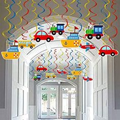 a hallway decorated with colorful streamers and cars hanging from it's ceiling in front of an open door