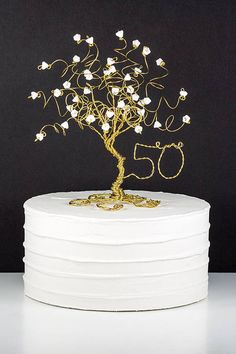 a white cake with a gold tree topper on it and the number fifty five