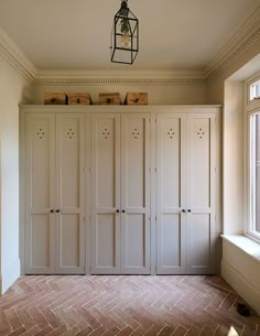 an empty room with several white cupboards and a light fixture hanging from the ceiling