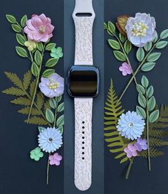 an apple watch with paper flowers and leaves on the front, along with a lace band