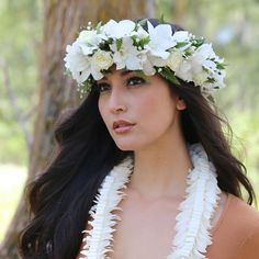 a woman with long hair wearing a flower crown on her head and white flowers in her hair