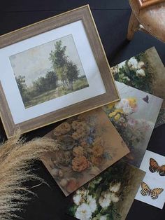 some pictures and flowers on a table with a butterfly in the frame next to them