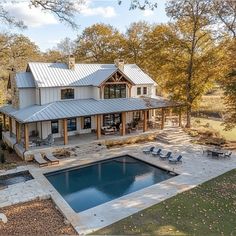 an aerial view of a house with a pool in the foreground and deck chairs around it