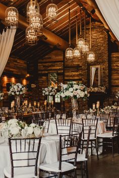 the tables are set up with white flowers and chandeliers hanging from the ceiling