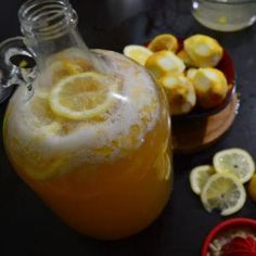 a pitcher filled with liquid next to sliced lemons and other ingredients on a table