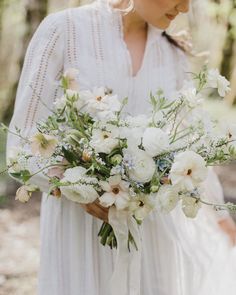 a woman holding a bouquet of white flowers