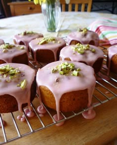 there are many cupcakes with pink icing on the cooling rack