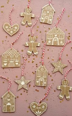 gingerbread cutout christmas ornaments hanging on a pink background with gold stars and glitters