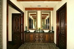 a large bathroom with double sinks and wooden doors leading to the other rooms in the house