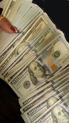 a woman's hand holding stacks of twenty dollar bills