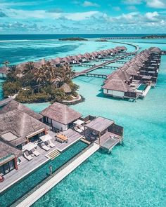 an aerial view of the water and beach with overwater huts in the ocean, surrounded by palm trees