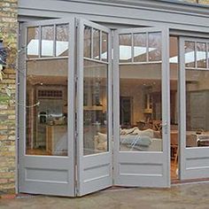 an open patio with french doors leading into the living room and dining area, in front of a brick building