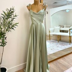 a mannequin wearing a long dress in front of a mirror with a potted plant