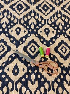 two pairs of scissors sitting on top of a black and white rug with pink, green, and yellow handles