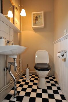 a black and white checkered floor in a bathroom with a toilet, sink and mirror