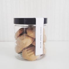 a glass jar filled with cookies sitting on top of a white table next to a wall