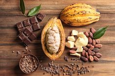 some nuts, chocolate and other food on top of a wooden table with green leaves