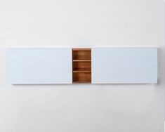 a white wall mounted shelf with two wooden sections on it's sides and one section above the other