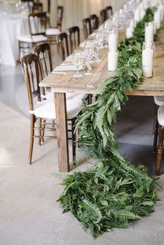 a long table with candles and greenery on it