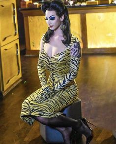 a woman in a tiger print dress sitting on a stool