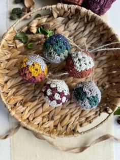 crocheted balls of yarn in a basket on a table with flowers and leaves