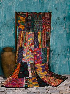 a large multicolored patchwork quilt on display in front of a blue wall