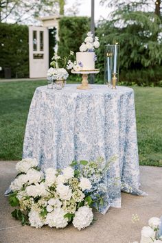 a blue and white wedding cake on top of a table with flowers in vases