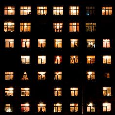 many windows are lit up at night with the lights turned on and one person standing in the window