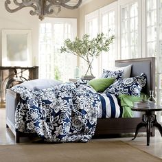 a bed sitting in a bedroom next to a table with a potted plant on top of it