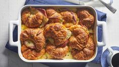 a casserole dish with ham and potatoes in it on a blue napkin next to a fork