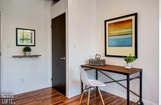 a room with a desk, chair and framed painting on the wall next to it