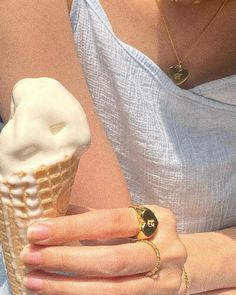 a woman is holding an ice cream cone in her right hand and wearing a gold ring