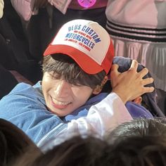 a boy in a red and white hat is hugging another boy with his arms around him