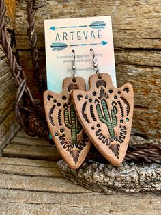 the earrings are made out of wood and have cactus designs on them, along with a card