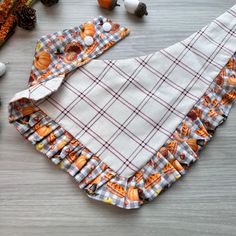 a plaid cloth with pumpkins on it sitting next to other autumn items and decorations