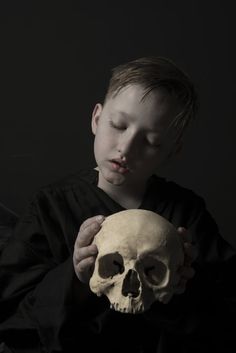 a young boy holding a human skull in his hands