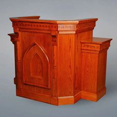 a wooden cabinet with an arched door on the front and side, sitting against a gray background