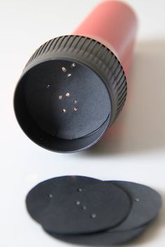 an open lipstick bottle with some tiny black dots on the top and one pink tube next to it